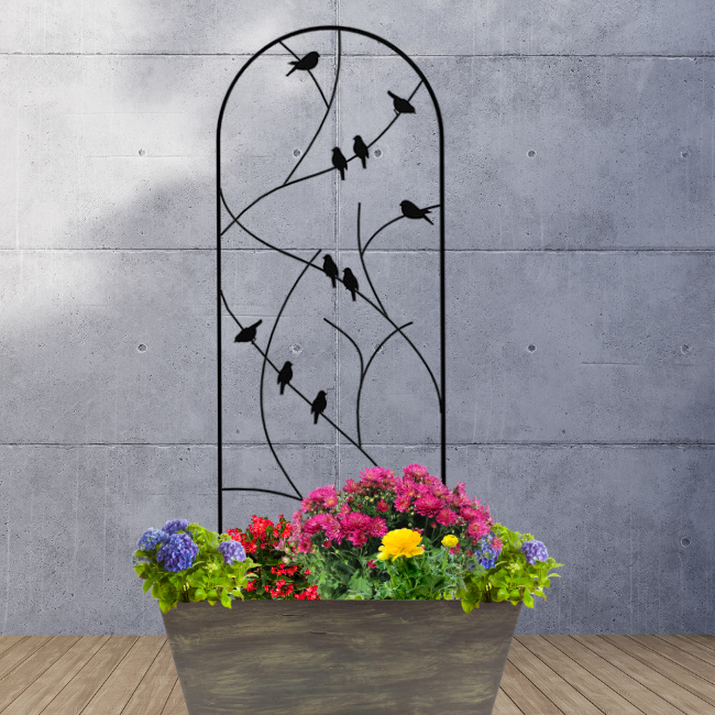 The Songbird Spiral Trellis installed in a garden with vibrant plants at its base. The charming bird silhouettes and sturdy steel frame provide an elegant support structure for climbing plants like roses or morning glories.